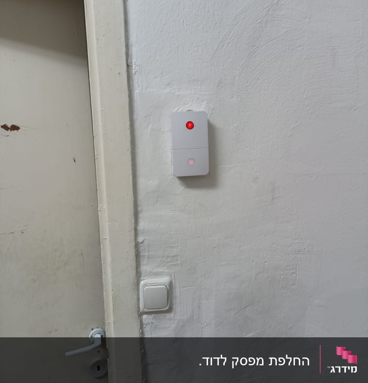מתג חשמלי עם נורית חיווי אדומה על קיר לבן